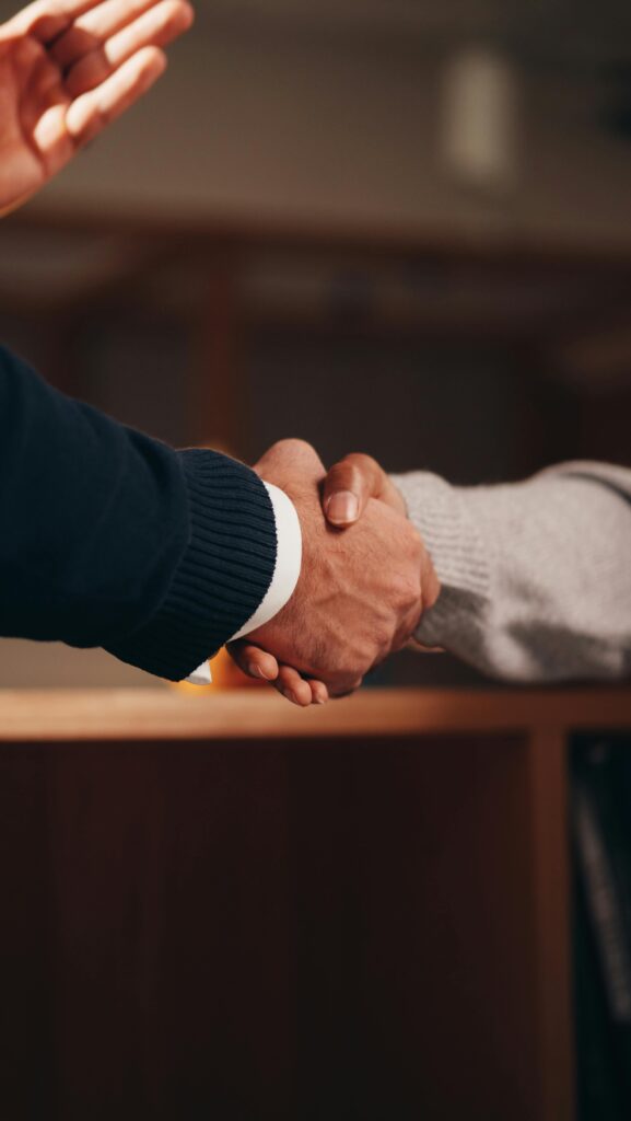 Two hands shaking in a professional setting, symbolizing business deal or agreement.